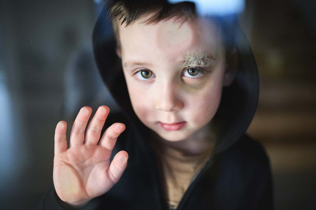 Child behind glass reaching out, need for child protective services.