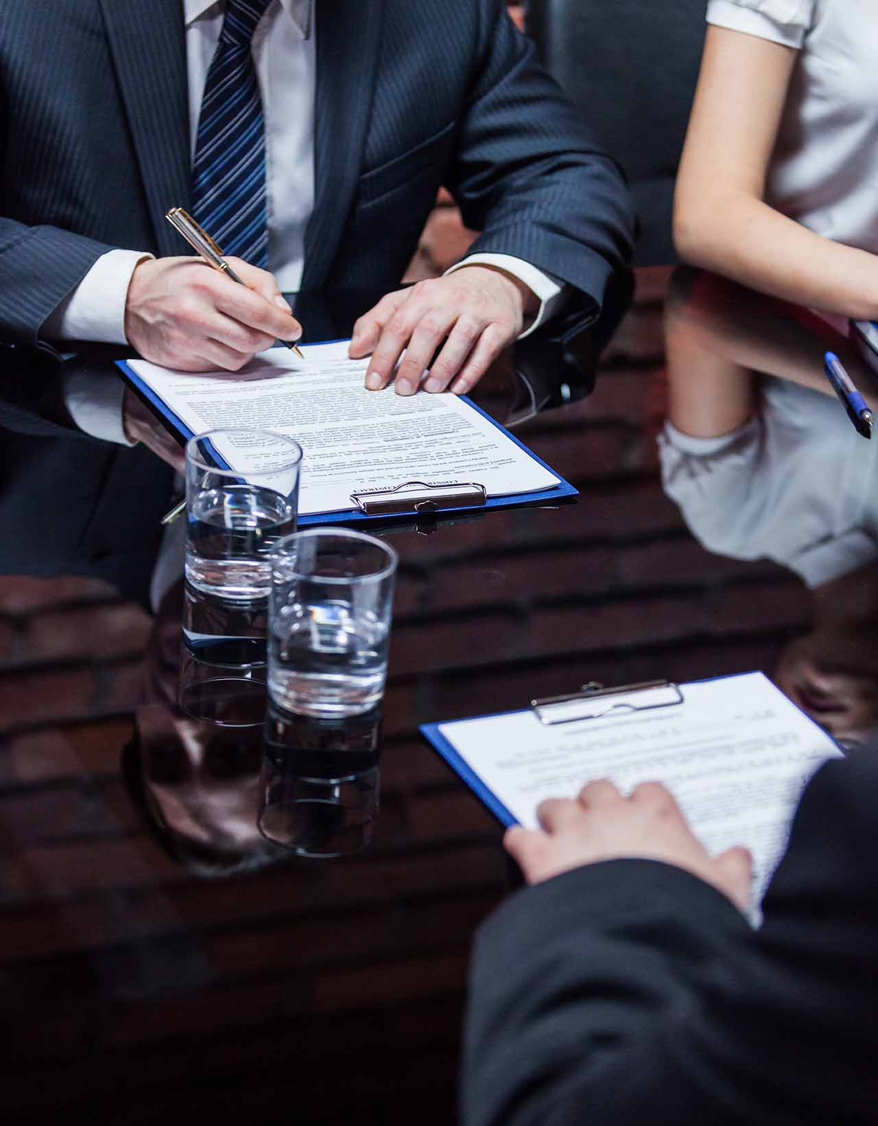 墨尔本商业诉讼律师 1 Business Professionals Reviewing And Signing Commercial Litigation Documents At A Conference Table.