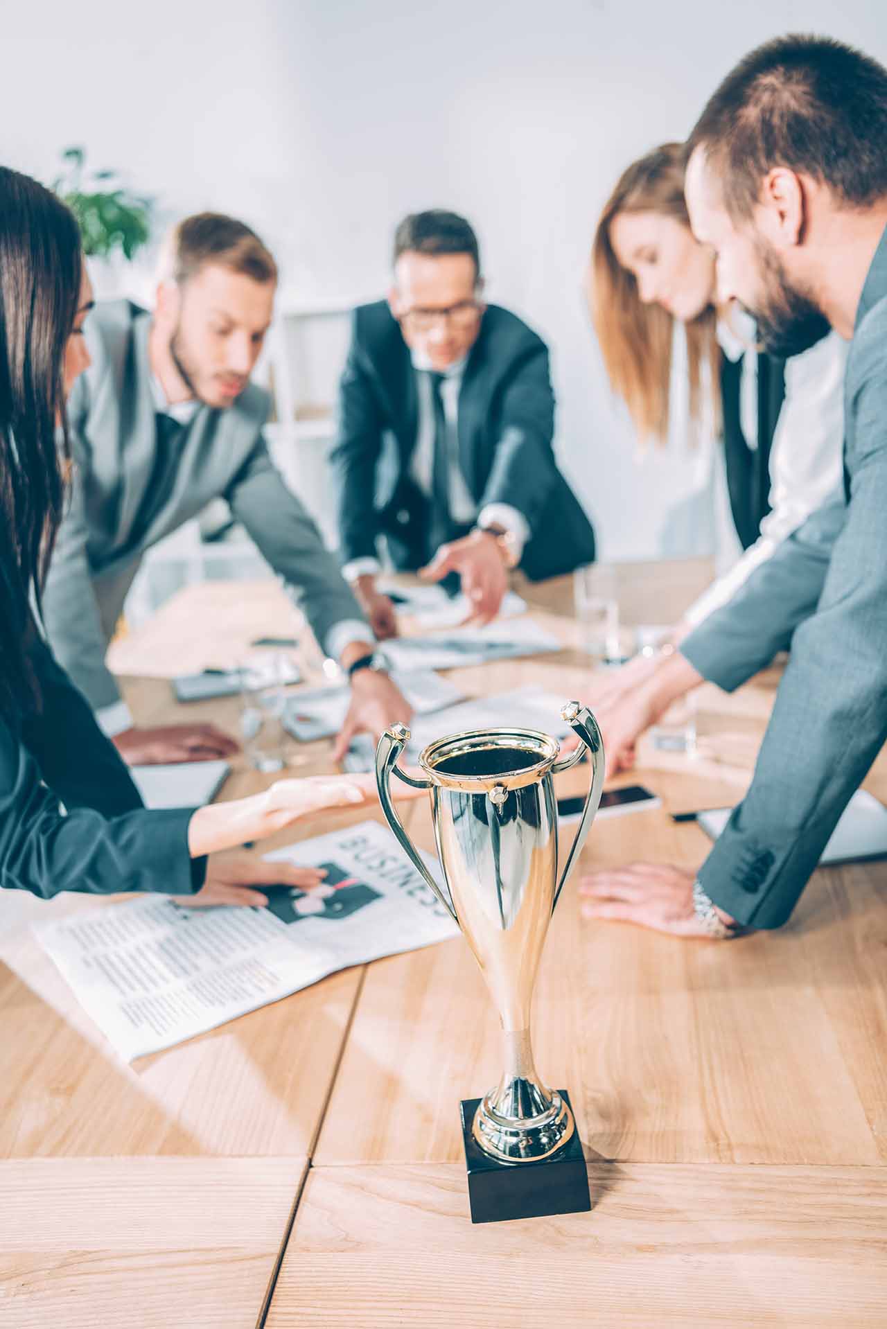 Business Lawyers In Melbourne 5 Collaborative Business Team Strategising Around A Table With A Trophy, Symbolising Success And Growth In Melbourne.