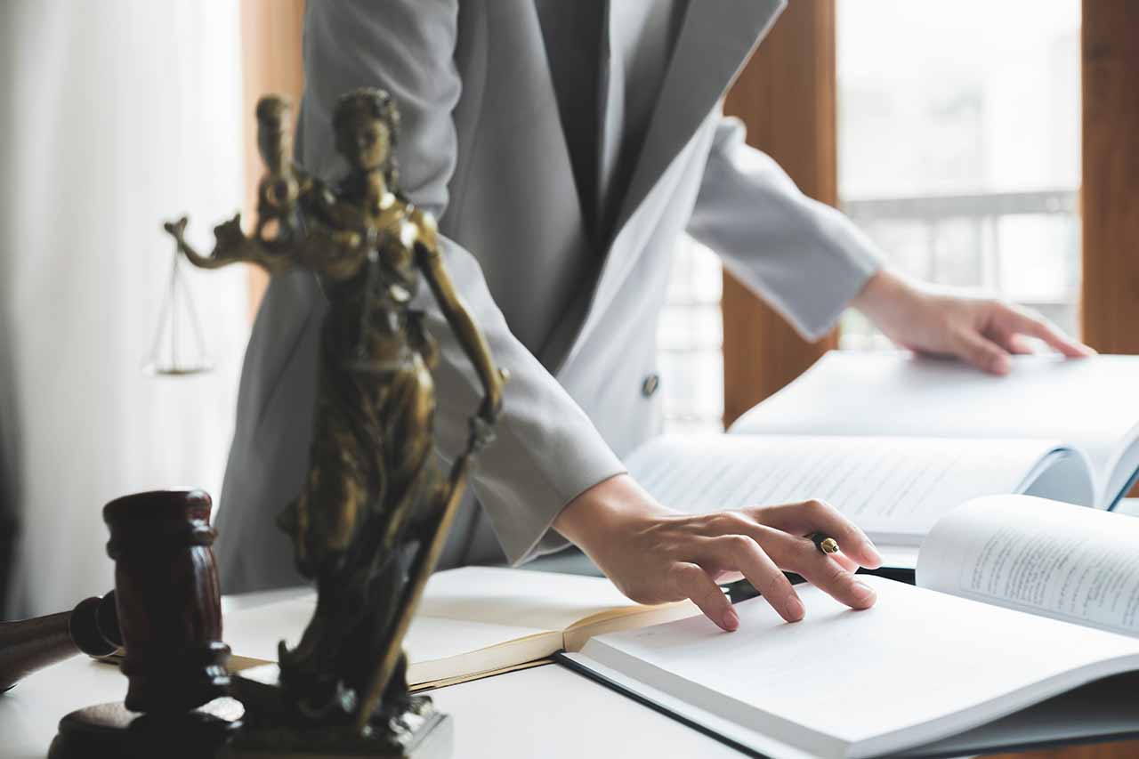 Binding Financial Agreements 9 A Lawyer Reviewing Legal Documents With A Statue Of Lady Justice And A Gavel In The Foreground, Representing Expert Asset Protection In Melbourne.
