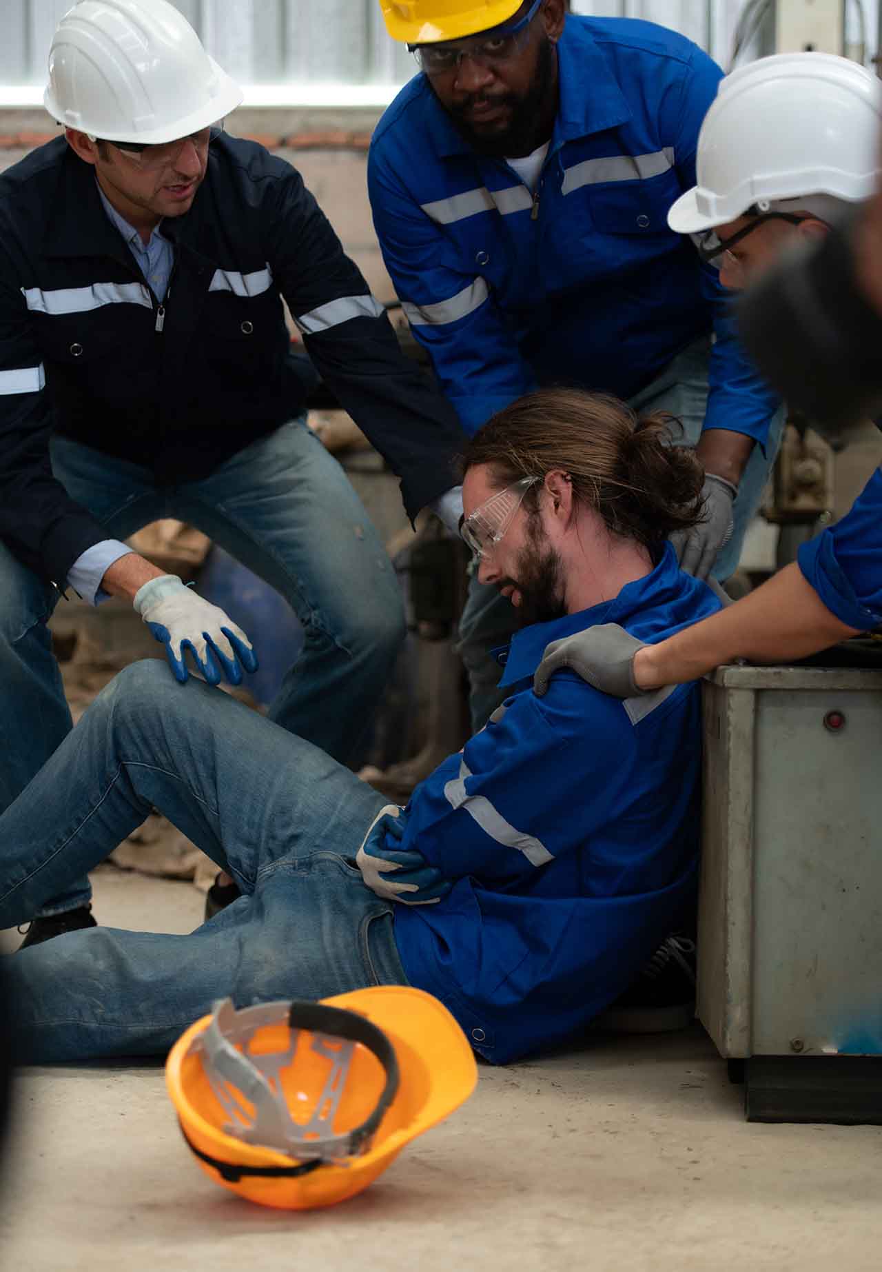 Work Injuries 5 Injured Worker Sitting On The Floor Supported By Colleagues At A Workplace.