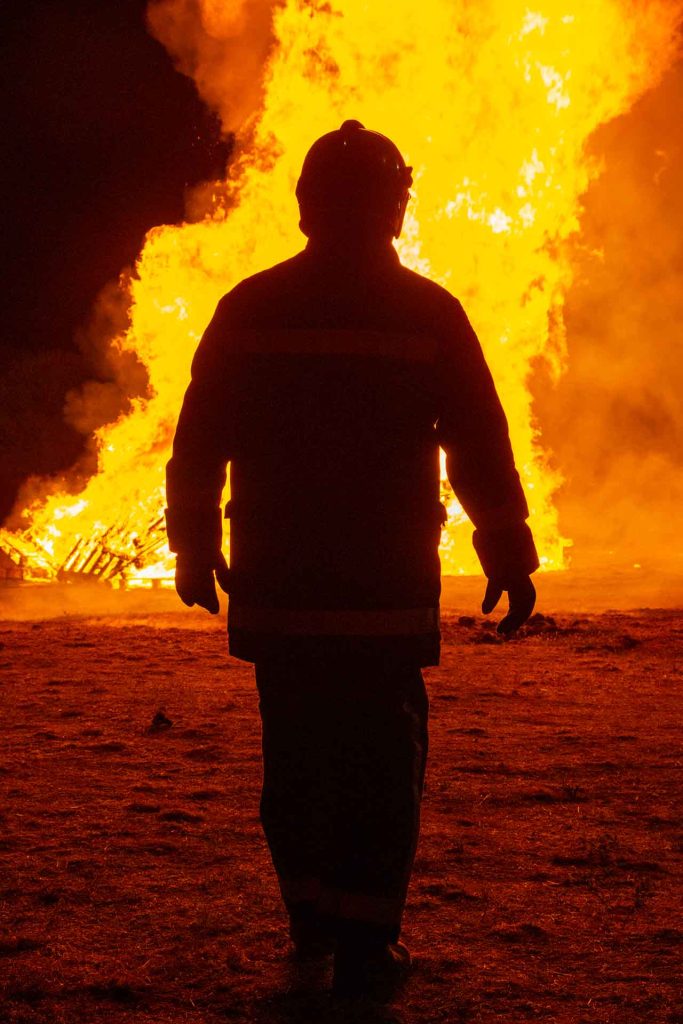 Silhouette of a firefighter standing before a blazing fire, symbolising arson and fire-related offences.