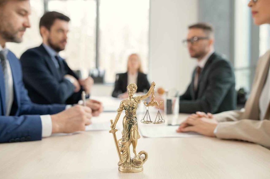Explore The Essential Types Of Lawyers In Melbourne 1 Lady Justice Statue On A Conference Table With Lawyers In Discussion