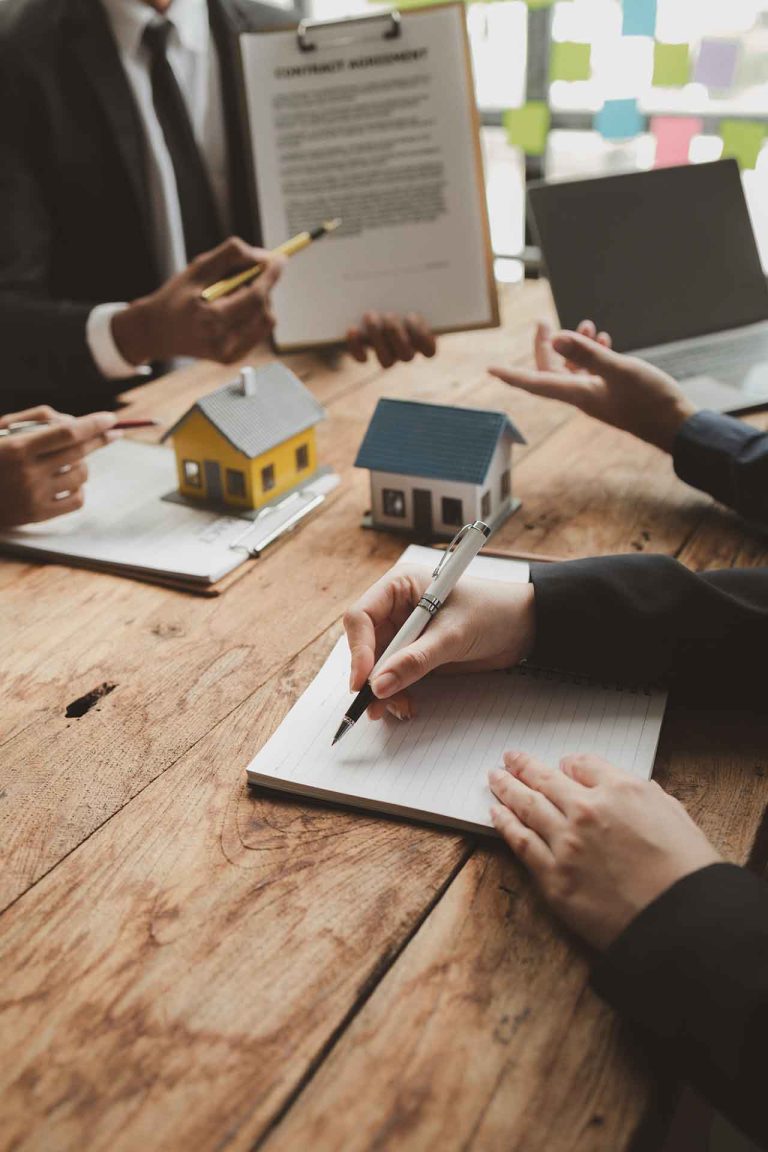 Legal consultation for a property dispute, featuring solicitors discussing contract agreements with clients, with miniature house models on a wooden table.